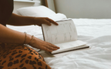 Woman sitting on bed turning pages in her diary to indicate a business owner creating thought leadership content