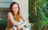 Amanda Lien, Founder of Minutiae Content Co., sits on her front porch with a laptop and diary in her arms