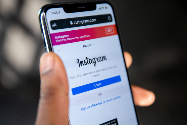 Man's hand holding a phone with the Instagram login on the screen, illustrating scheduling posts on Instagram