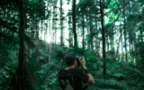 Man taking a photo in a camera in a lush forest to illustrate creating content for Instagram account