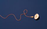 Orange Ear Plugs with Curved String Reach to Ear on Blue Background Directly above View. 4 tips for RevOps teams to filter out the noise and focus on the big picture