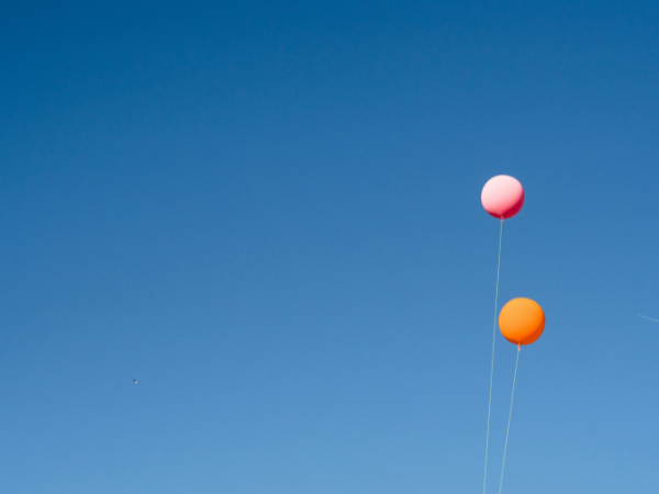 A pink and orange balloon set against the backdrop of a clear blue sky to illustrate get verified on Bluesky
